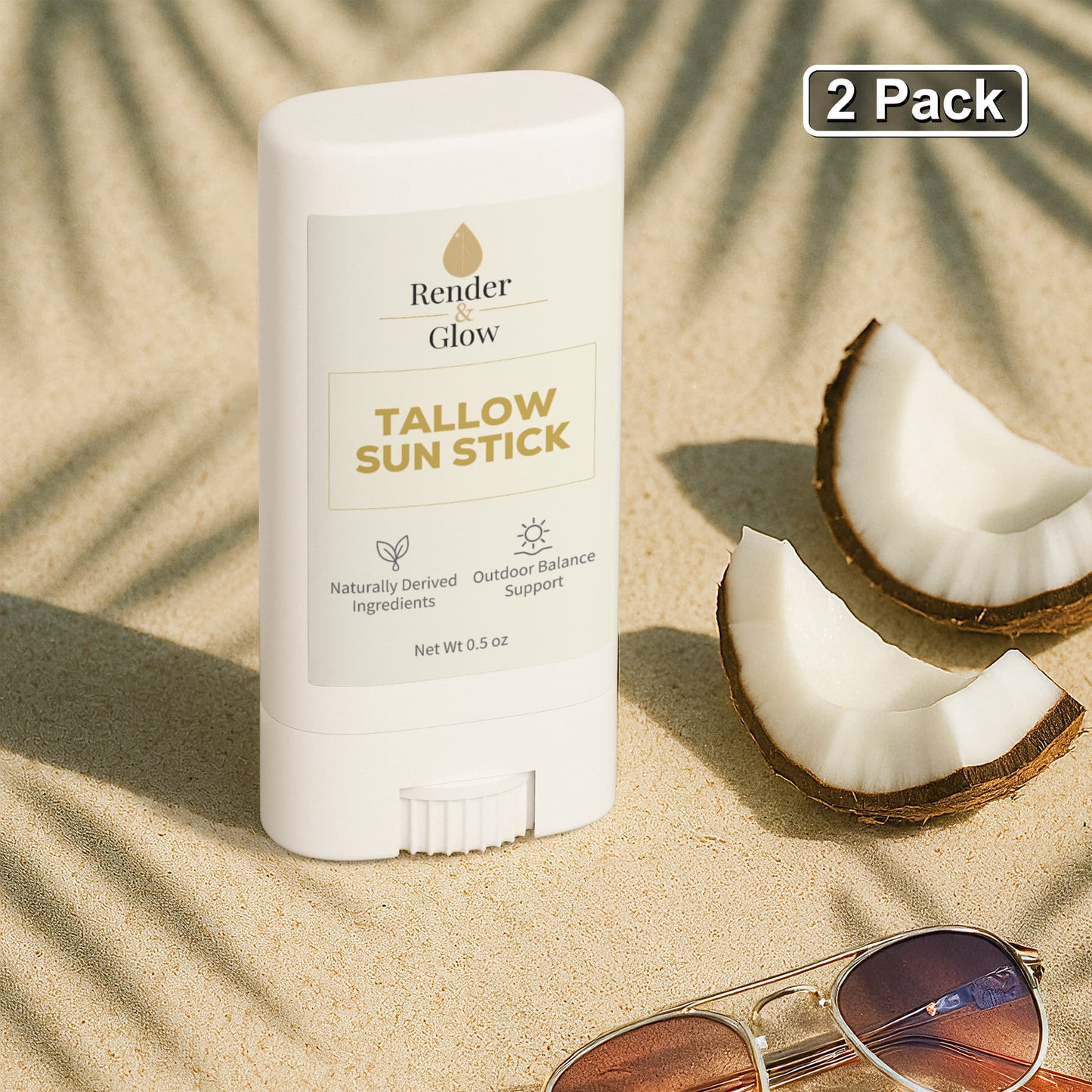 Render & Glow Tallow Sun Stick (2-Pack) with zinc oxide sits on sand near coconut halves.