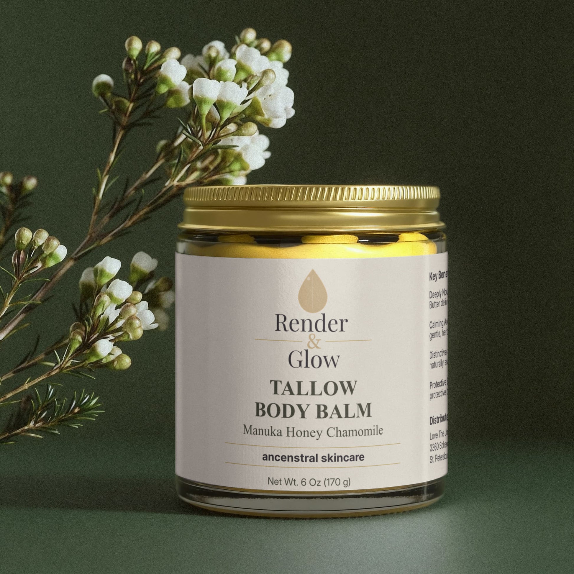 A jar of Render & Glow Tallow Body Balm sits beside white flowers on a green background.