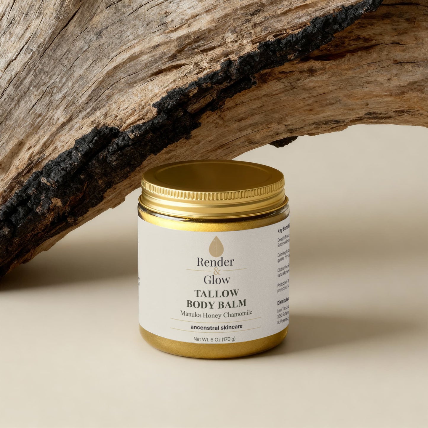 A gold jar of Render & Glow Tallow Body Balm offers intense daily hydration, set on beige beside rustic wood.