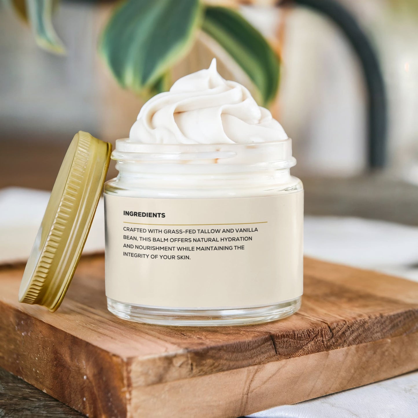 A Render & Glow Whipped Tallow Skin Balm jar with a gold lid sits on a wooden board, label showing ingredients.