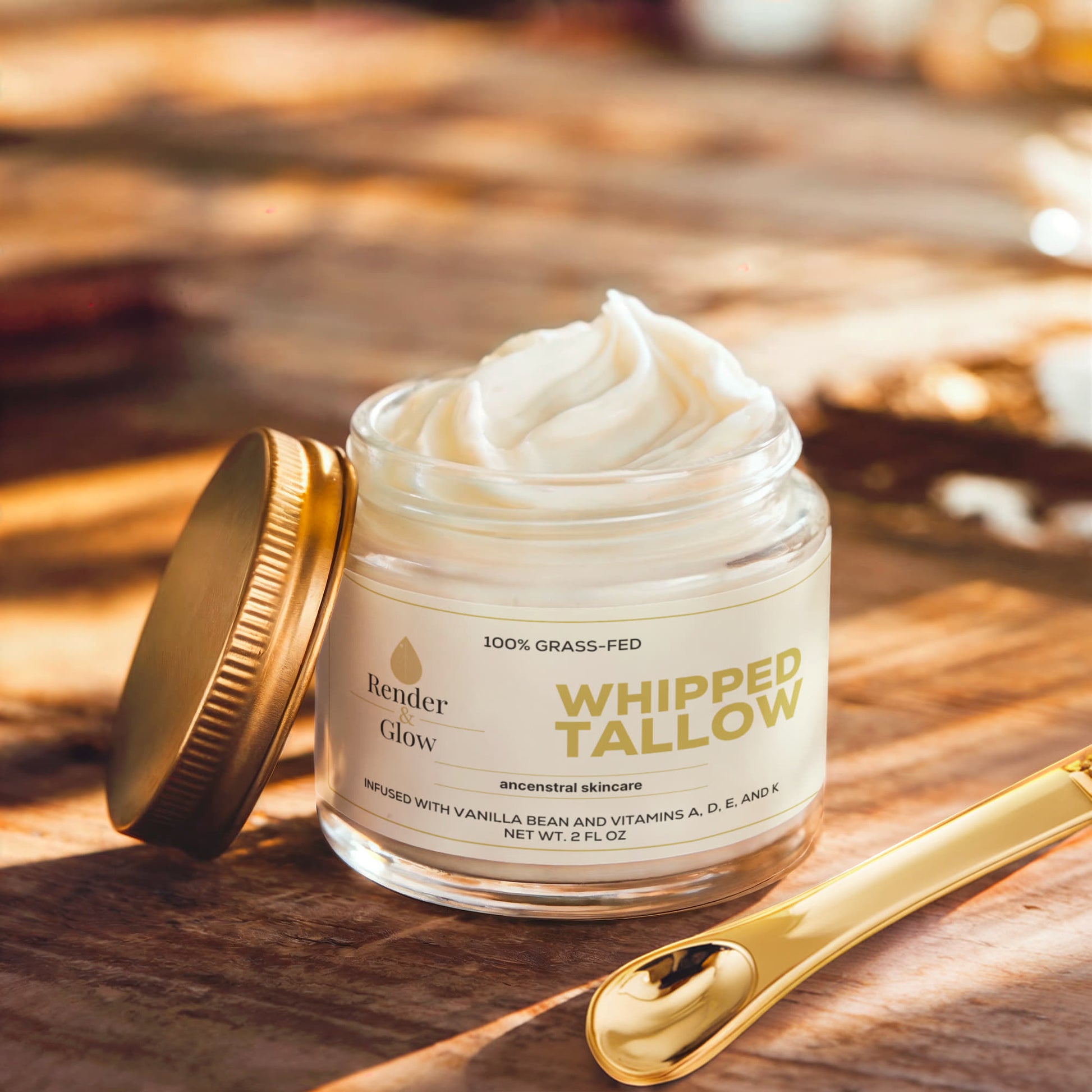 Render & Glow Whipped Tallow Skin Balm with a golden lid and spoon sits on wood, illuminated by sunlight.