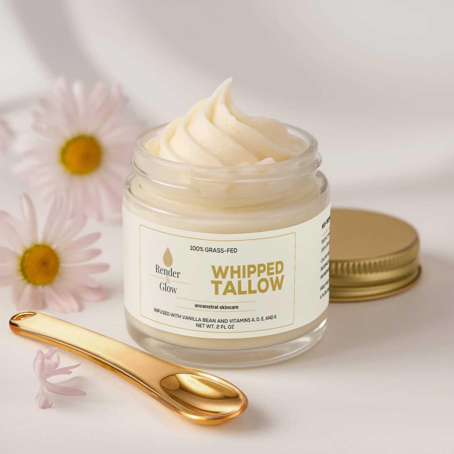 Render & Glow Whipped Tallow Skin Balm in a glass jar with gold lid, gold spoon, and pink flowers.